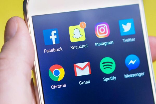 A person's hand holding a smartphone displaying social media and communication apps.